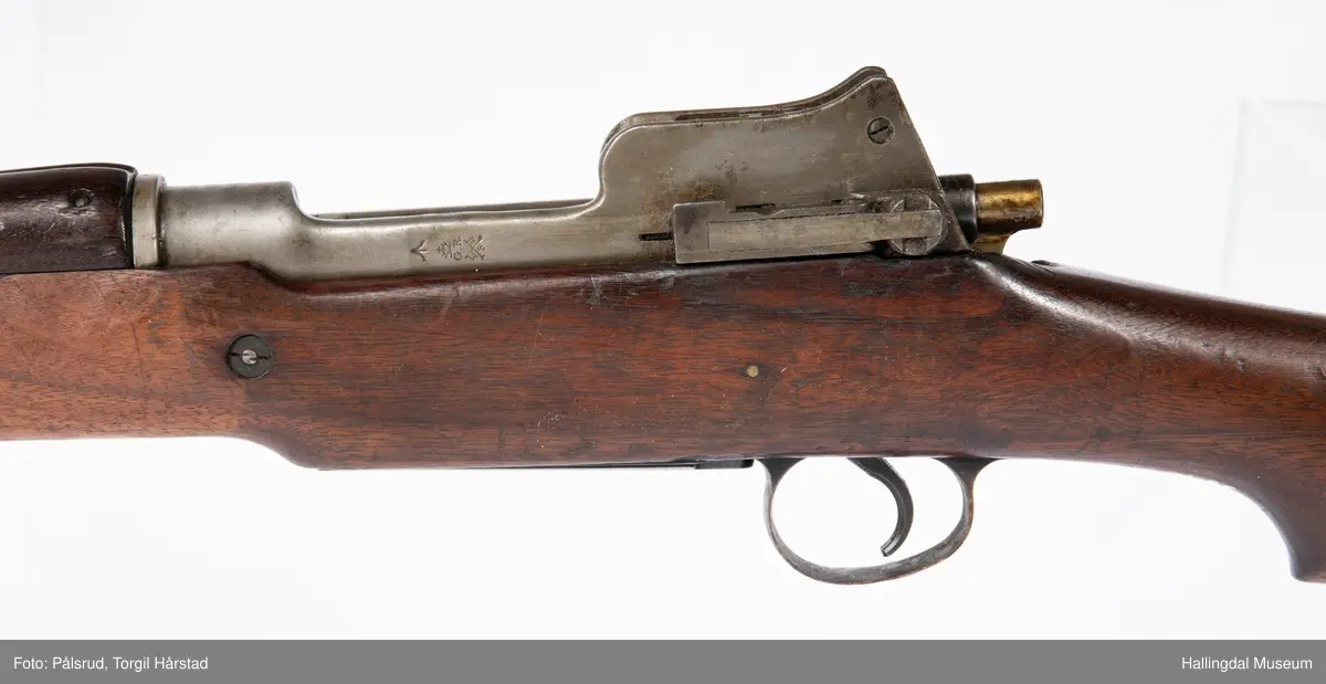 Engelsk Lee-Enfield rifle. Brukt under andre verdenskrig i Norge. 
Framstokken er noe avkappet - mulig i forbindelse med ombygging til jaktvåpen. 
Kaliber: .303 British. 
Geværet har et surret hampetau til reim - ikke original.
