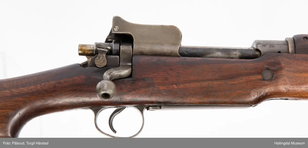 Engelsk Lee-Enfield rifle. Brukt under andre verdenskrig i Norge. 
Framstokken er noe avkappet - mulig i forbindelse med ombygging til jaktvåpen. 
Kaliber: .303 British. 
Geværet har et surret hampetau til reim - ikke original.