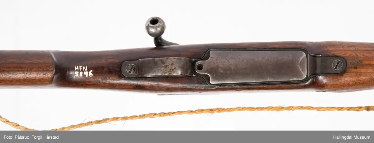 Engelsk Lee-Enfield rifle. Brukt under andre verdenskrig i Norge. 
Framstokken er noe avkappet - mulig i forbindelse med ombygging til jaktvåpen. 
Kaliber: .303 British. 
Geværet har et surret hampetau til reim - ikke original.