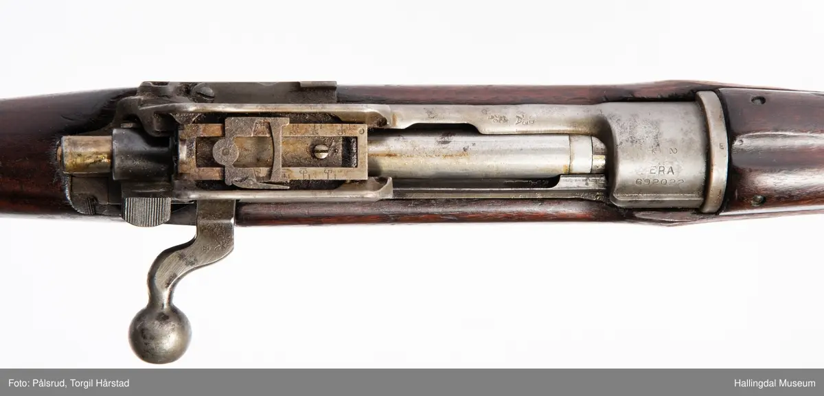 Engelsk Lee-Enfield rifle. Brukt under andre verdenskrig i Norge. 
Framstokken er noe avkappet - mulig i forbindelse med ombygging til jaktvåpen. 
Kaliber: .303 British. 
Geværet har et surret hampetau til reim - ikke original.