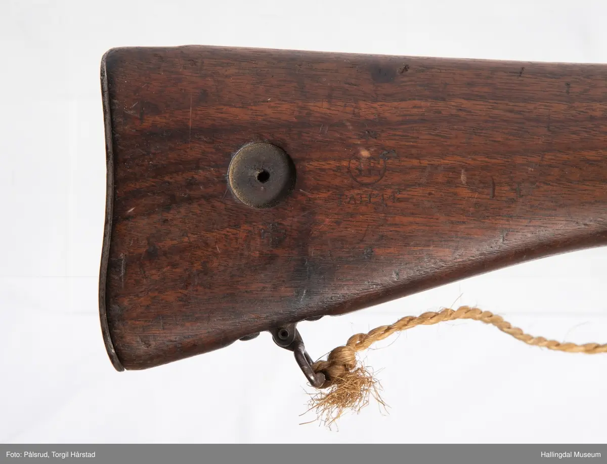 Engelsk Lee-Enfield rifle. Brukt under andre verdenskrig i Norge. 
Framstokken er noe avkappet - mulig i forbindelse med ombygging til jaktvåpen. 
Kaliber: .303 British. 
Geværet har et surret hampetau til reim - ikke original.