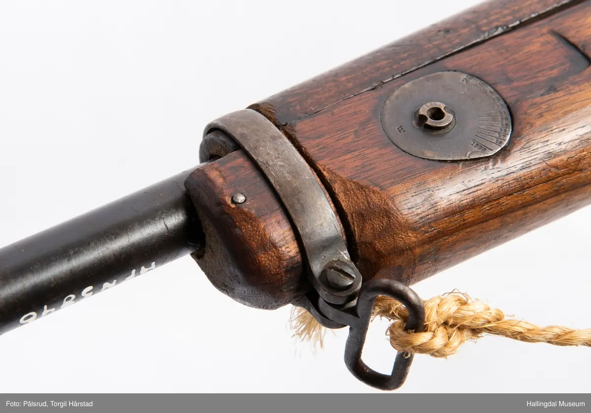 Engelsk Lee-Enfield rifle. Brukt under andre verdenskrig i Norge. 
Framstokken er noe avkappet - mulig i forbindelse med ombygging til jaktvåpen. 
Kaliber: .303 British. 
Geværet har et surret hampetau til reim - ikke original.