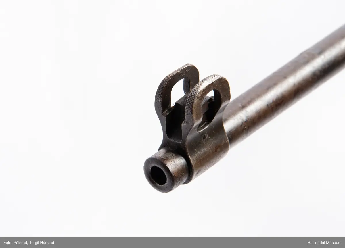 Engelsk Lee-Enfield rifle. Brukt under andre verdenskrig i Norge. 
Framstokken er noe avkappet - mulig i forbindelse med ombygging til jaktvåpen. 
Kaliber: .303 British. 
Geværet har et surret hampetau til reim - ikke original.
