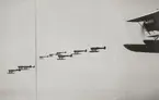 Fjärde spaningsdivisionens flygplan i luften, 1932. Nio flygplan S 5 flyger i formation. I förgrunden syns flygplan S 6 nummer 4392.
Flygbild.

Text vid foto: 