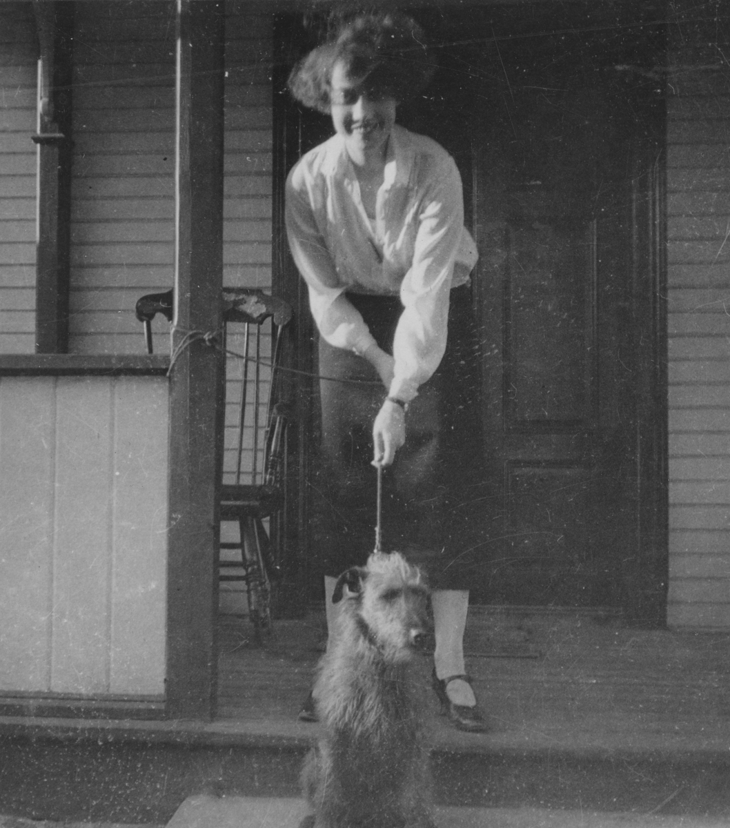 Porträttfoto av Anna Linderstam och en hund vid en trappa i Malmslätt, 1925.

Text vid foto: "Malmslätt. Flickan och Råttan våren 1925."