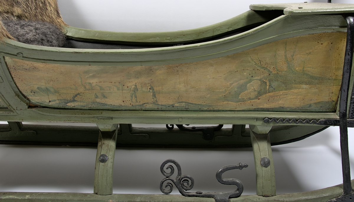 Släde, enspännare av furuträ. Grönmålad. Med järnbeslag. Kuskbockssadel ("hundsfott") samt plats för en passagerare. I sätet en infälld lucka, förvaringsutrymme. Kuskbocksbrädan samt sätets sid- och ryggstycken stoppade med hö, foder juteväv, klädda med grävlingskinn. Framtill stänkskydd för passageraren av svart impregnerad duk

Rikt dekorerad med målningar i Rokokostil.