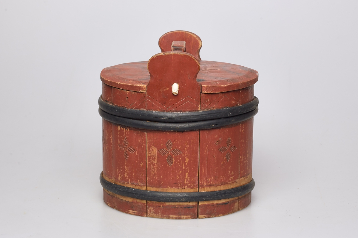 Lagging med tre gjorder, men én mangler. Lokk og ører, uten bein. Formen er rund, lokket er utenpåliggende og har håndtak. Påmalt rød farge, og dekorert med roser og streker. Brukt til oppbevaring av ost.