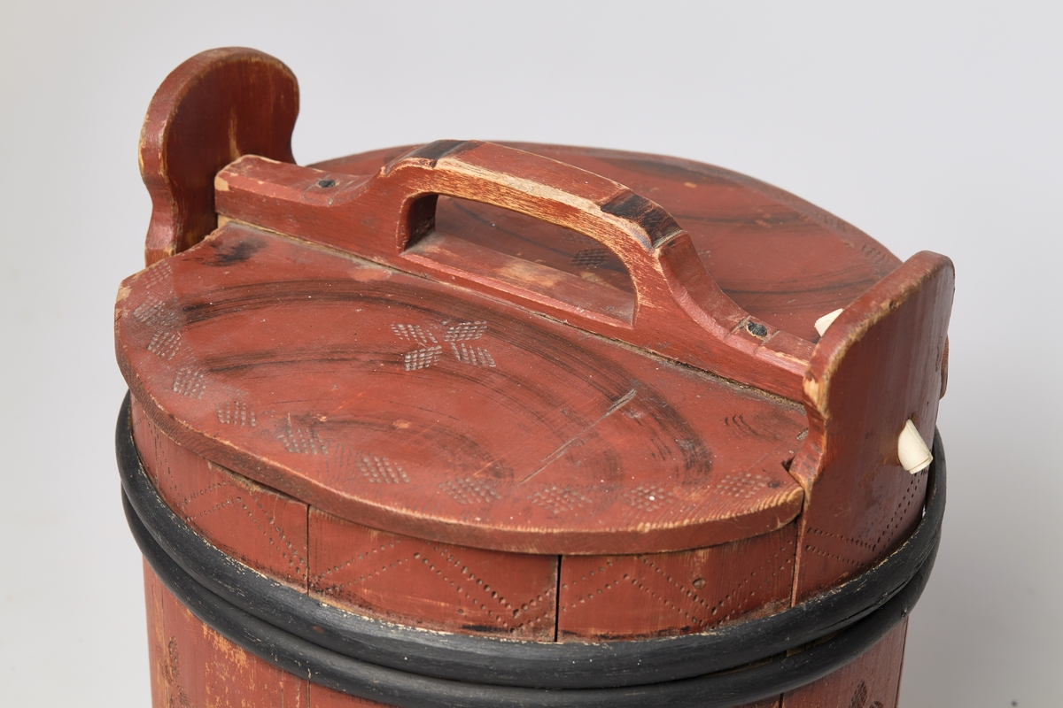 Lagging med tre gjorder, men én mangler. Lokk og ører, uten bein. Formen er rund, lokket er utenpåliggende og har håndtak. Påmalt rød farge, og dekorert med roser og streker. Brukt til oppbevaring av ost.