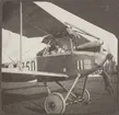 Motorkörning inför start av flygplan SW 12 (Albatros) märkt nummer 750, cirka 1917-1925. Flygförare i sitsen och två mekaniker runt flygplanet.