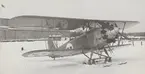 Flygplan J 4, Heinkel HD 19 står med skidor, vintertid, framför hangar på F 2 Hägernäs, cirka 1929-1930.

Text vid foto: 