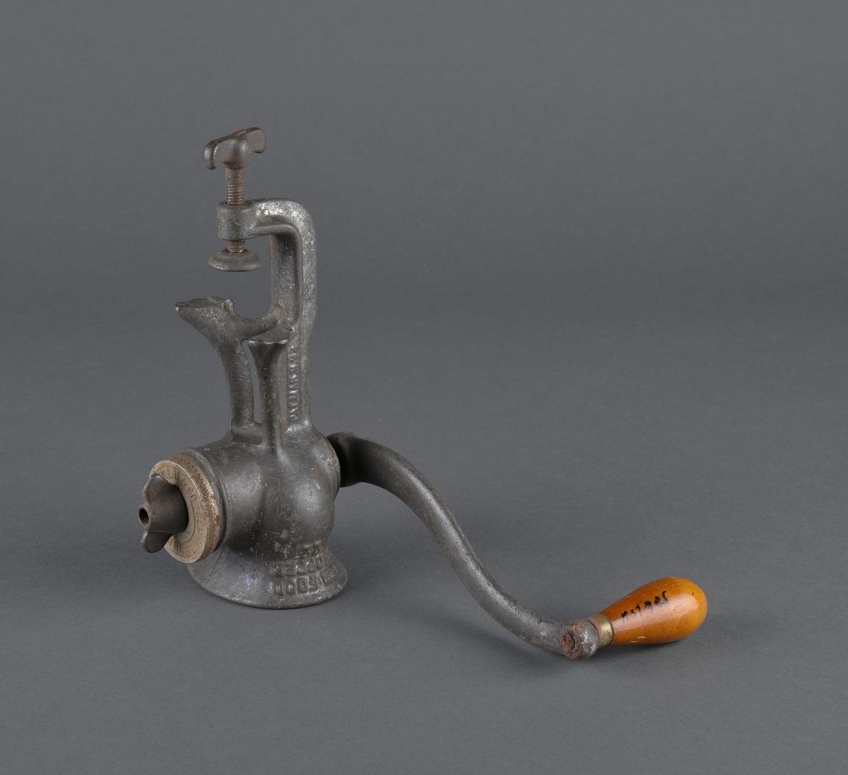 Redskap til kverning av mandler.
Laget i metall, for å feste til bord eller annet. Sveiv med trehåndtak