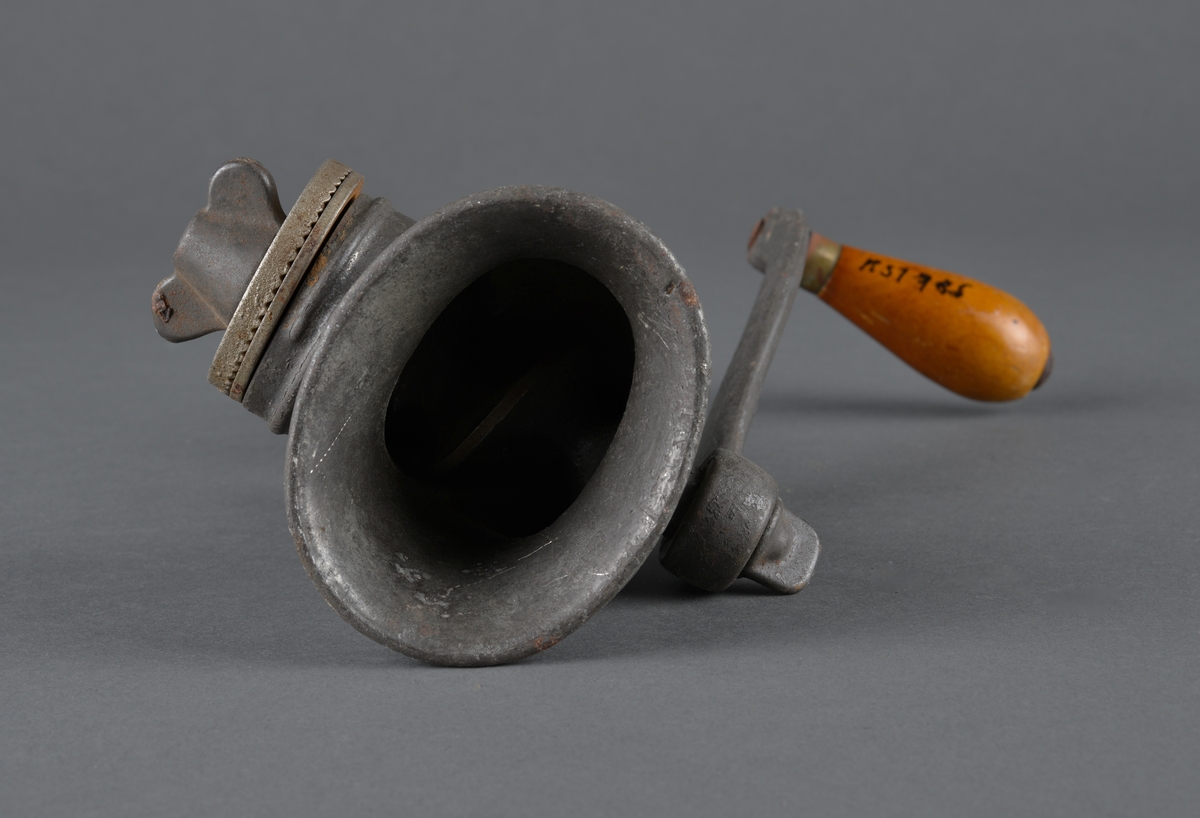 Redskap til kverning av mandler.
Laget i metall, for å feste til bord eller annet. Sveiv med trehåndtak