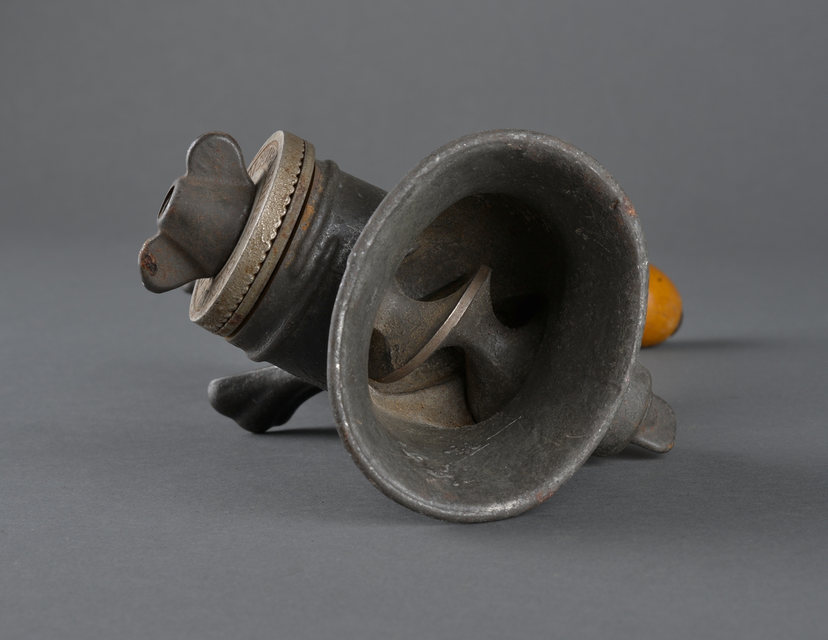 Redskap til kverning av mandler.
Laget i metall, for å feste til bord eller annet. Sveiv med trehåndtak