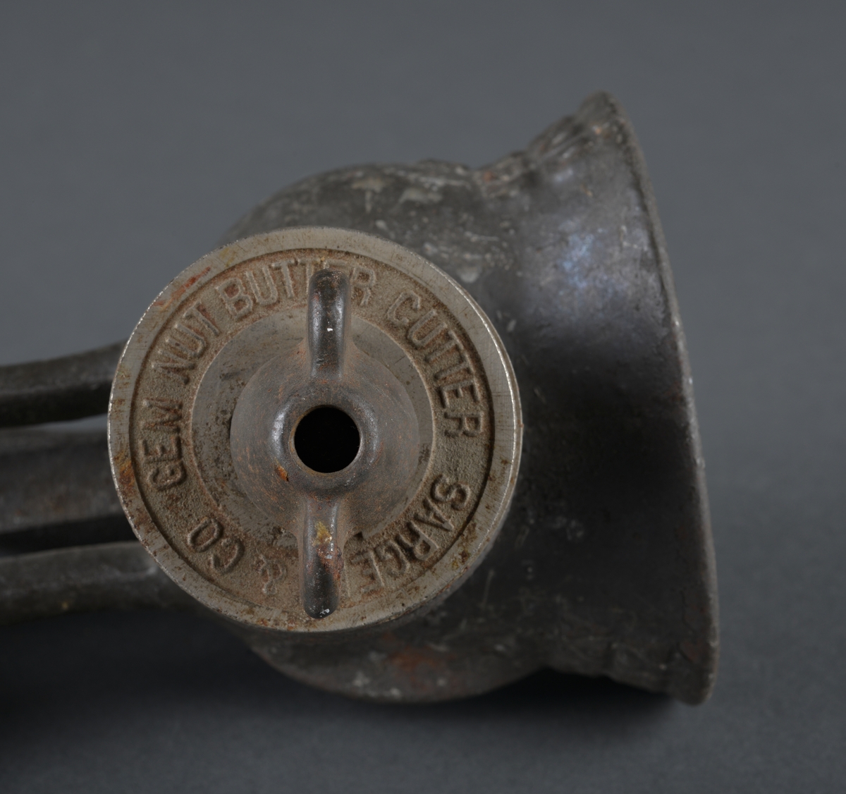 Redskap til kverning av mandler.
Laget i metall, for å feste til bord eller annet. Sveiv med trehåndtak