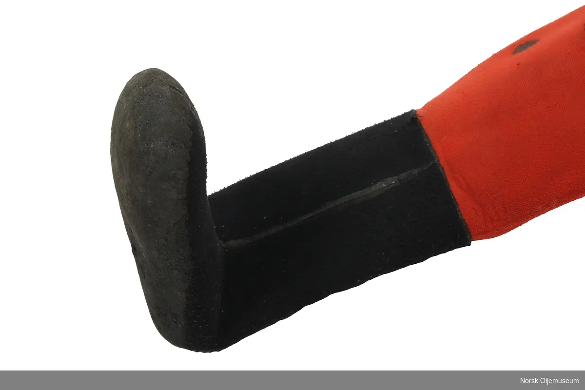 Tørrdrakt av neopren. Dykkerdrakten er av merke Poseidon og det er utført reparasjoner og endringer på drakten. Den har påsatte svarte sko som ikke er originale og utventil er plassert øverst på venstre arm. Foran på brystet har den to påsydde runde lapper av neopren. Drakten har slitasje på knærne fra bruk.