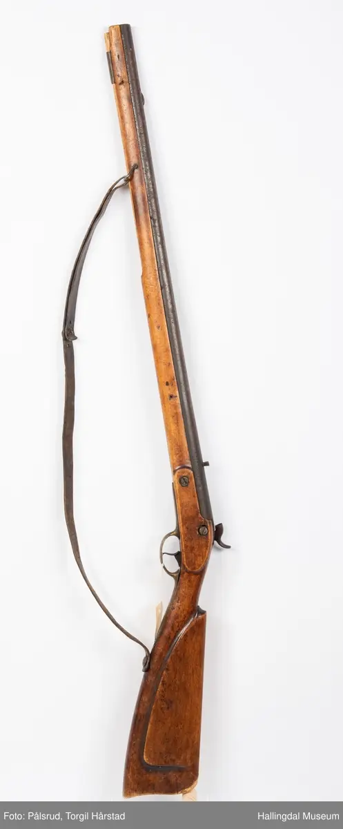 Gevær, modell fra 1769 - 1793, som er ombygd fra flintlås til perkusjonslås. Vært brukt av "Norske Gevorbne Jeger Corps" og senere av soldat nr. 90 i "Telemarkske Nationale jeger Corps Westenfjeldske Compani" i perioden 1818 - 1839. Geværet mangler kolbekappe, men har antatt original reim i brunt lær med messingknapp. Ladestokk i tre.