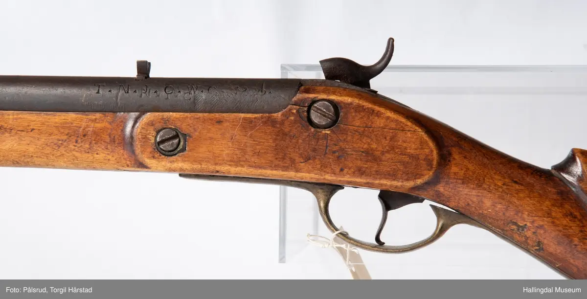 Gevær, modell fra 1769 - 1793, som er ombygd fra flintlås til perkusjonslås. Vært brukt av "Norske Gevorbne Jeger Corps" og senere av soldat nr. 90 i "Telemarkske Nationale jeger Corps Westenfjeldske Compani" i perioden 1818 - 1839. Geværet mangler kolbekappe, men har antatt original reim i brunt lær med messingknapp. Ladestokk i tre.