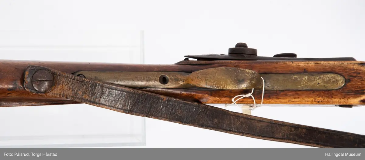 Gevær, modell fra 1769 - 1793, som er ombygd fra flintlås til perkusjonslås. Vært brukt av "Norske Gevorbne Jeger Corps" og senere av soldat nr. 90 i "Telemarkske Nationale jeger Corps Westenfjeldske Compani" i perioden 1818 - 1839. Geværet mangler kolbekappe, men har antatt original reim i brunt lær med messingknapp. Ladestokk i tre.