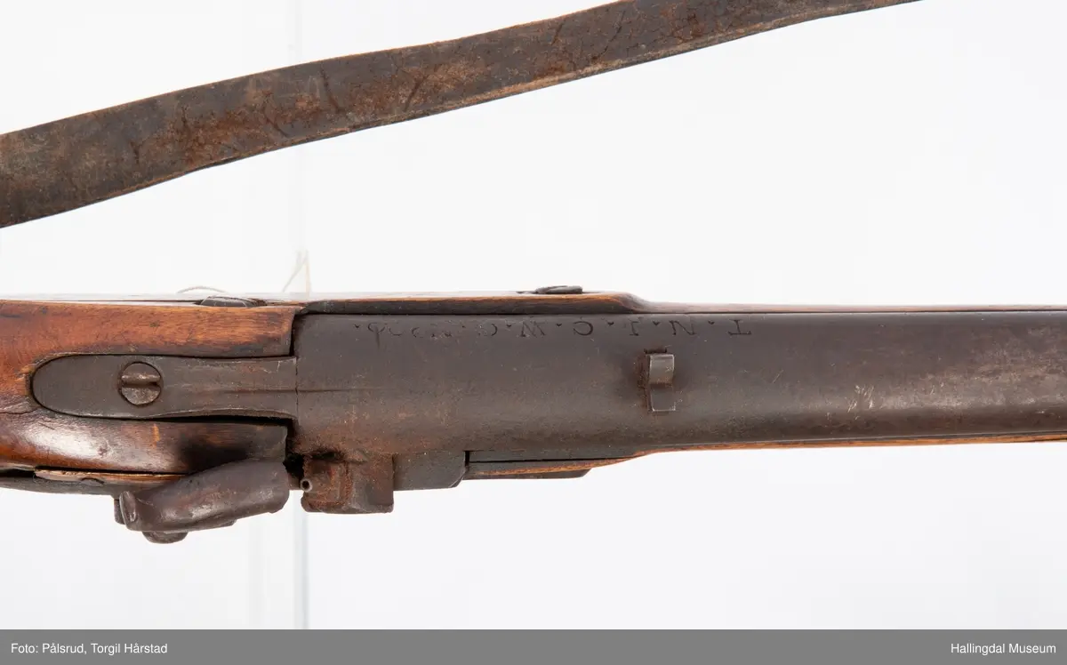Gevær, modell fra 1769 - 1793, som er ombygd fra flintlås til perkusjonslås. Vært brukt av "Norske Gevorbne Jeger Corps" og senere av soldat nr. 90 i "Telemarkske Nationale jeger Corps Westenfjeldske Compani" i perioden 1818 - 1839. Geværet mangler kolbekappe, men har antatt original reim i brunt lær med messingknapp. Ladestokk i tre.