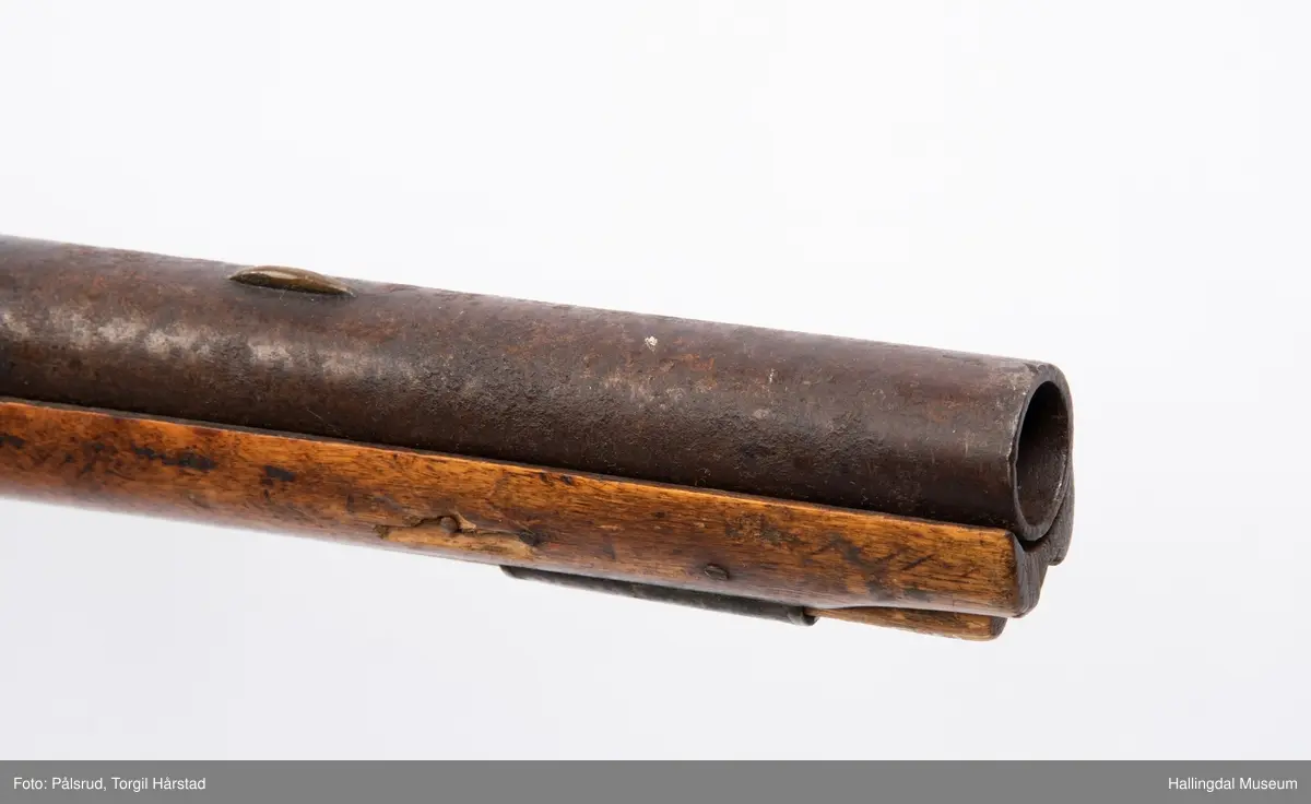 Gevær, modell fra 1769 - 1793, som er ombygd fra flintlås til perkusjonslås. Vært brukt av "Norske Gevorbne Jeger Corps" og senere av soldat nr. 90 i "Telemarkske Nationale jeger Corps Westenfjeldske Compani" i perioden 1818 - 1839. Geværet mangler kolbekappe, men har antatt original reim i brunt lær med messingknapp. Ladestokk i tre.