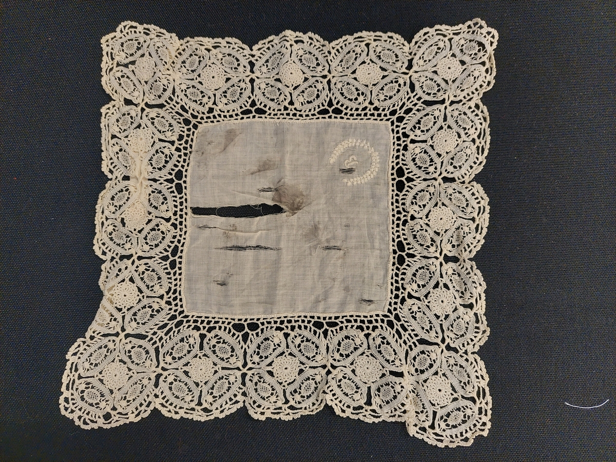 lommetørkle med blondekant og monogram.