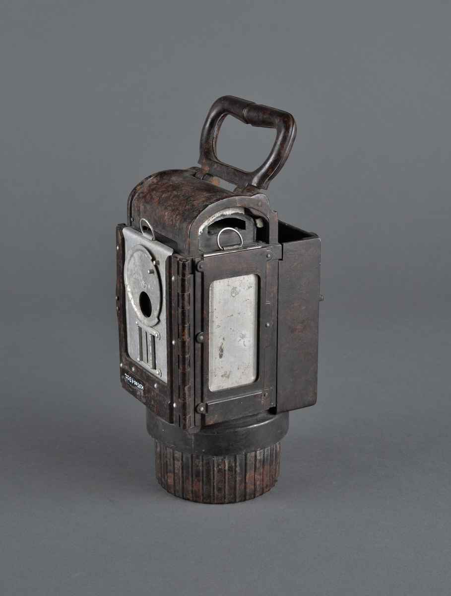 Dette er en bunkerslykt fra 2. verdenskrig. Lykta ble brukt i bunkersannleg av tyske styrker. 
Kan blendes ved å skyve et metallfilter foran lysåpningen. 
Håndtak og festeanordning bak for å henge opp lykta på vegg eller annet.