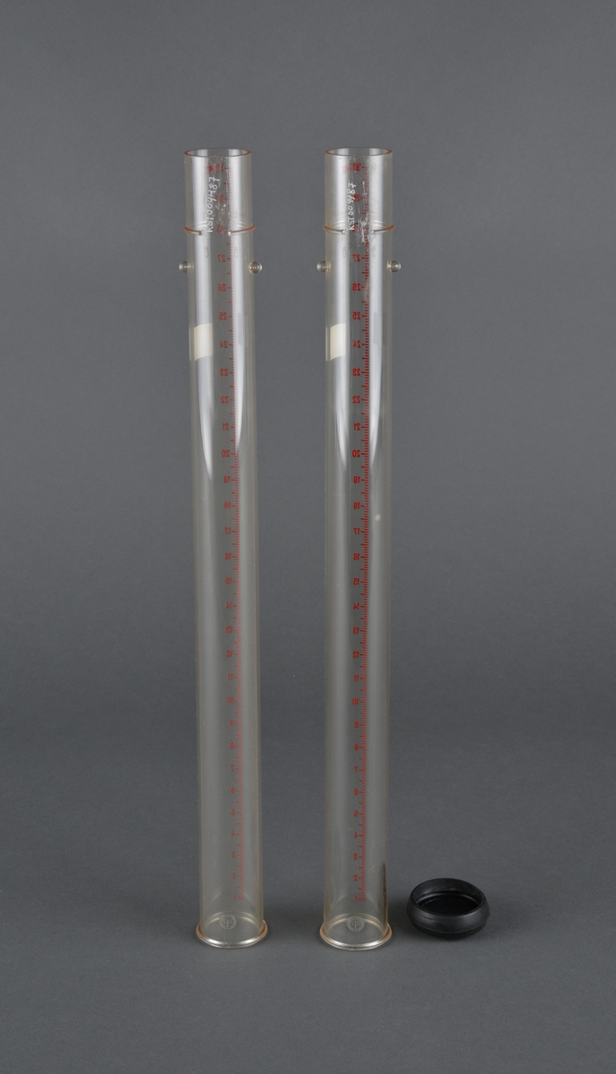 Sylinderformet rør med anvisning på sidene 1 - 30 kg i rød trykk. 
Det ene røret har et svart plastlokk i bunnen, det andre mangler. 
I overkant på begge rørene er det støpt inn to tapper. Kanskje for oppheng i stativ eller lignende.