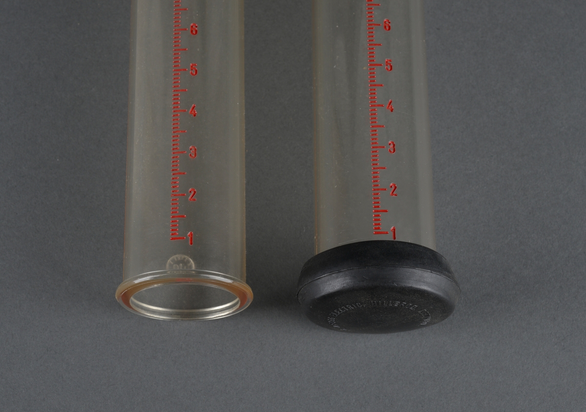 Sylinderformet rør med anvisning på sidene 1 - 30 kg i rød trykk. 
Det ene røret har et svart plastlokk i bunnen, det andre mangler. 
I overkant på begge rørene er det støpt inn to tapper. Kanskje for oppheng i stativ eller lignende.