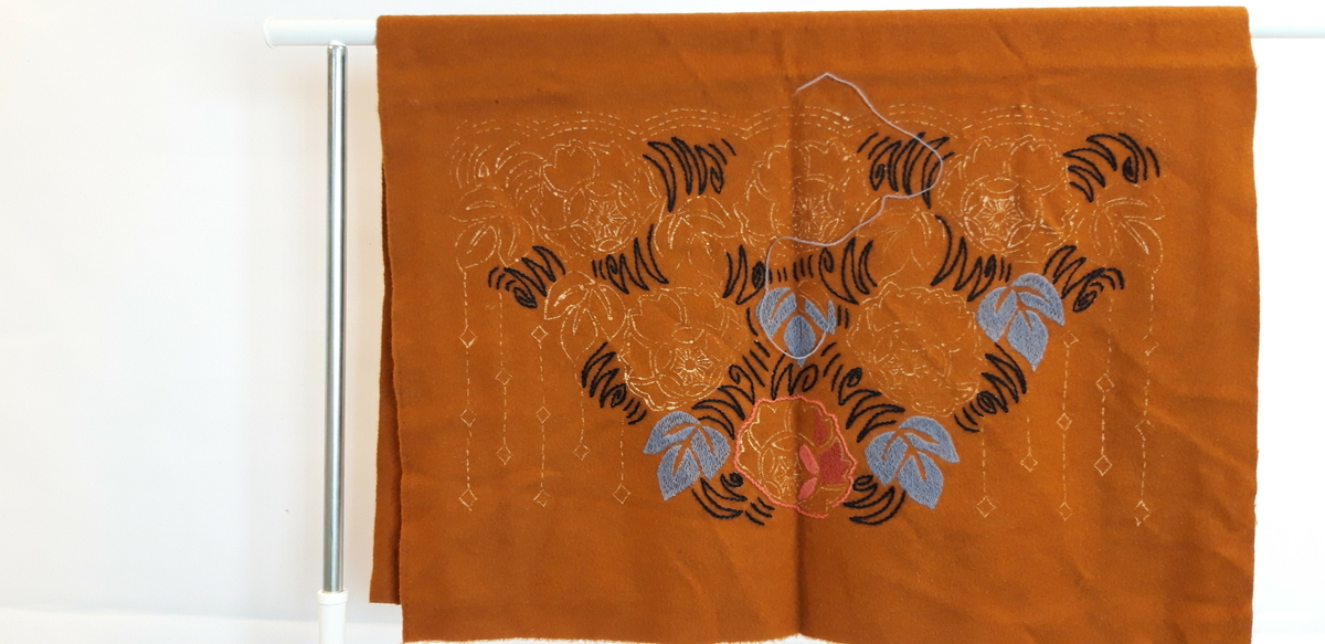 2 stoffstykker, rustrødt med uferdig broderi, antagelig møbeltrekk
