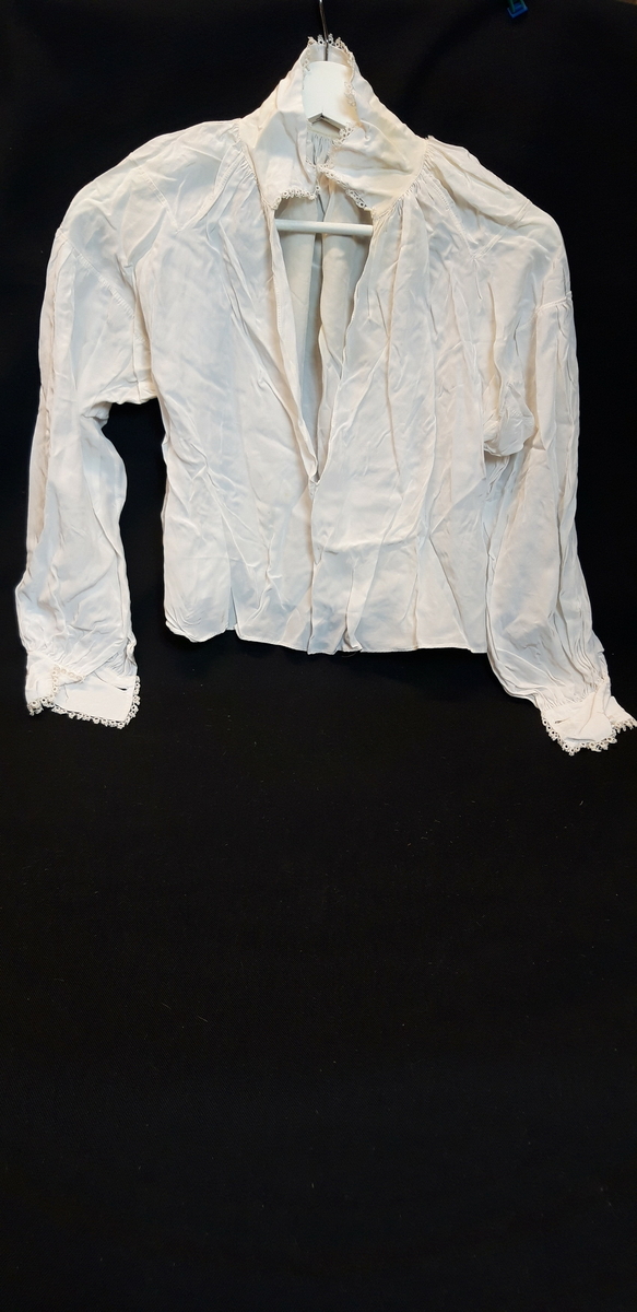 1 skjorte, hvit nylon i primærsnitt, dekorert med nuperellekanter, trulig brukt som bunadskjorte.