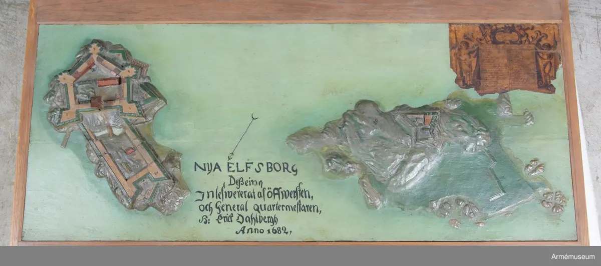 Modellen har påskrift: "Nya Elfsborg Desseing inlefwererat af Öffwersten och General quartermestaren h: Erich Dahlbergh anno 1682".

Modellen är 565x1355 mm och utförd av två ekbrädor med en ursprunglig tjocklek av 50 mm. Holmarna är skurna direkt ur plattan, som vid vattnet har sin minsta tjocklek av 25 mm. Även själva befästningarna är skurna i ett med plattan, endast husen och tornet är skurna för sig och fastsatta. I övre högra hörnet sitter en påklistrad lapp med förklaringar. I inventariet 1768 hade modellen nr 2, men siffran finns inte längre kvar. 
Förmodligen vid renoveringen på 1880-talet har man skrivit av texten, som sedan av misstag hamnat på baksidan av Bohus fästning. 1939 rengjordes modellen från fernissa och smuts, flagnande färg fästes och modellen mattfernissades.

Texten omges av voluter och putti med slöjor och smala pyramider, överst en kartusch med två putti. "Delination af Nya Elfsborg och des uthanwärck med Assp-holmen afmätit
och förfärdigat anno 1678 d. 1 november."

"Explication öfwer Bastionerne sampt andre notable orthers nampn".
1. Hummeren
2. Hwalfisken
3. Haffrunn
4. Delfin
5. Norrstiärnan
6. Porttornet
7. Catsamatan hwar uthi dhen öfwerste håller predikan för guarnizon
8. Commendantens logumente
9. Under Commendantens logumente
10. Prästens och Condeutörens logumenter
11. Lieutnampters och Fändrichers logumenter
12. Constabler och handtlangare
13. Wachtmästarens logumente
14. Archliemästarens
15. Wacht Corps de Guarde
16. Sortier eller löönportar
17. Brunn och friskt watn
18. Ravalinen
19. Hornwärcket
20. Baracquen
21. Kalekboden
22. Uthi hornwärcket sortier
23. Norr Horn
24. Wäster Horn
25. af master ophugne ravalin
26. Hamn för båthar
27. Tvänne Brunnar med färskt watn
28. Bryggian hwarest farkoster anläggia
29. Asspholmen
30. dhet dher nyss upparbetadhe Tenaliewärcket
31. Ett opkastat Trensiement emot watenet

Nederdelen av texten är borta där förmodligen David Lydings signatur stått.
