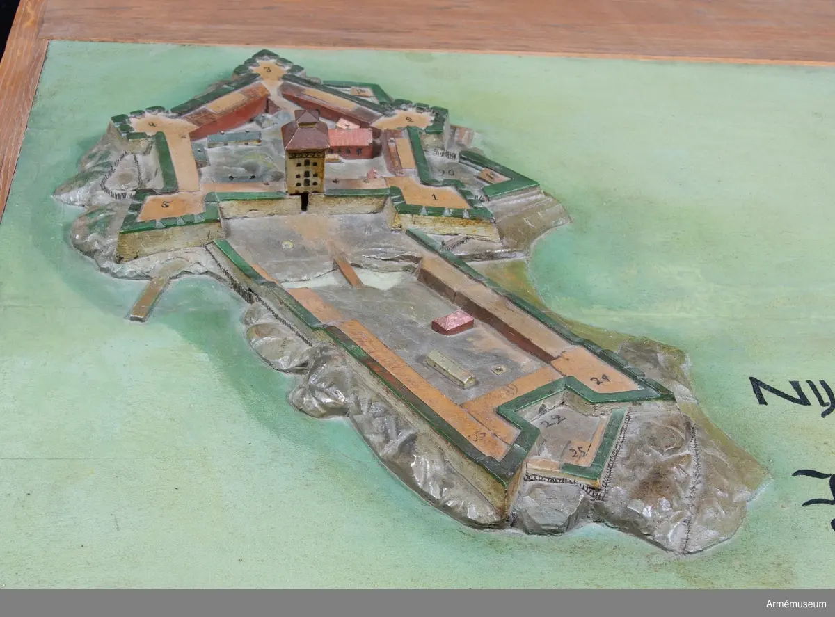 Modellen har påskrift: "Nya Elfsborg Desseing inlefwererat af Öffwersten och General quartermestaren h: Erich Dahlbergh anno 1682".

Modellen är 565x1355 mm och utförd av två ekbrädor med en ursprunglig tjocklek av 50 mm. Holmarna är skurna direkt ur plattan, som vid vattnet har sin minsta tjocklek av 25 mm. Även själva befästningarna är skurna i ett med plattan, endast husen och tornet är skurna för sig och fastsatta. I övre högra hörnet sitter en påklistrad lapp med förklaringar. I inventariet 1768 hade modellen nr 2, men siffran finns inte längre kvar. 
Förmodligen vid renoveringen på 1880-talet har man skrivit av texten, som sedan av misstag hamnat på baksidan av Bohus fästning. 1939 rengjordes modellen från fernissa och smuts, flagnande färg fästes och modellen mattfernissades.

Texten omges av voluter och putti med slöjor och smala pyramider, överst en kartusch med två putti. "Delination af Nya Elfsborg och des uthanwärck med Assp-holmen afmätit
och förfärdigat anno 1678 d. 1 november."

"Explication öfwer Bastionerne sampt andre notable orthers nampn".
1. Hummeren
2. Hwalfisken
3. Haffrunn
4. Delfin
5. Norrstiärnan
6. Porttornet
7. Catsamatan hwar uthi dhen öfwerste håller predikan för guarnizon
8. Commendantens logumente
9. Under Commendantens logumente
10. Prästens och Condeutörens logumenter
11. Lieutnampters och Fändrichers logumenter
12. Constabler och handtlangare
13. Wachtmästarens logumente
14. Archliemästarens
15. Wacht Corps de Guarde
16. Sortier eller löönportar
17. Brunn och friskt watn
18. Ravalinen
19. Hornwärcket
20. Baracquen
21. Kalekboden
22. Uthi hornwärcket sortier
23. Norr Horn
24. Wäster Horn
25. af master ophugne ravalin
26. Hamn för båthar
27. Tvänne Brunnar med färskt watn
28. Bryggian hwarest farkoster anläggia
29. Asspholmen
30. dhet dher nyss upparbetadhe Tenaliewärcket
31. Ett opkastat Trensiement emot watenet

Nederdelen av texten är borta där förmodligen David Lydings signatur stått.