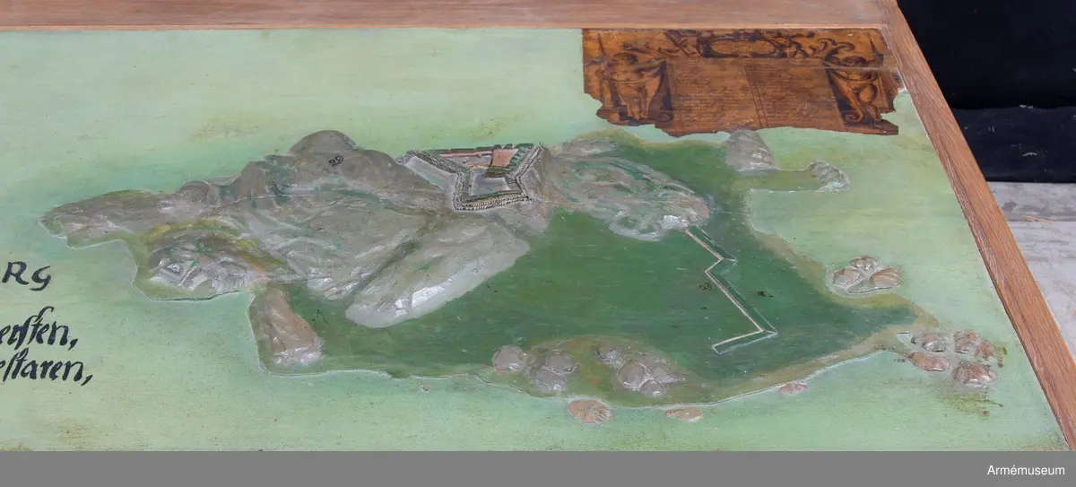 Modellen har påskrift: "Nya Elfsborg Desseing inlefwererat af Öffwersten och General quartermestaren h: Erich Dahlbergh anno 1682".

Modellen är 565x1355 mm och utförd av två ekbrädor med en ursprunglig tjocklek av 50 mm. Holmarna är skurna direkt ur plattan, som vid vattnet har sin minsta tjocklek av 25 mm. Även själva befästningarna är skurna i ett med plattan, endast husen och tornet är skurna för sig och fastsatta. I övre högra hörnet sitter en påklistrad lapp med förklaringar. I inventariet 1768 hade modellen nr 2, men siffran finns inte längre kvar. 
Förmodligen vid renoveringen på 1880-talet har man skrivit av texten, som sedan av misstag hamnat på baksidan av Bohus fästning. 1939 rengjordes modellen från fernissa och smuts, flagnande färg fästes och modellen mattfernissades.

Texten omges av voluter och putti med slöjor och smala pyramider, överst en kartusch med två putti. "Delination af Nya Elfsborg och des uthanwärck med Assp-holmen afmätit
och förfärdigat anno 1678 d. 1 november."

"Explication öfwer Bastionerne sampt andre notable orthers nampn".
1. Hummeren
2. Hwalfisken
3. Haffrunn
4. Delfin
5. Norrstiärnan
6. Porttornet
7. Catsamatan hwar uthi dhen öfwerste håller predikan för guarnizon
8. Commendantens logumente
9. Under Commendantens logumente
10. Prästens och Condeutörens logumenter
11. Lieutnampters och Fändrichers logumenter
12. Constabler och handtlangare
13. Wachtmästarens logumente
14. Archliemästarens
15. Wacht Corps de Guarde
16. Sortier eller löönportar
17. Brunn och friskt watn
18. Ravalinen
19. Hornwärcket
20. Baracquen
21. Kalekboden
22. Uthi hornwärcket sortier
23. Norr Horn
24. Wäster Horn
25. af master ophugne ravalin
26. Hamn för båthar
27. Tvänne Brunnar med färskt watn
28. Bryggian hwarest farkoster anläggia
29. Asspholmen
30. dhet dher nyss upparbetadhe Tenaliewärcket
31. Ett opkastat Trensiement emot watenet

Nederdelen av texten är borta där förmodligen David Lydings signatur stått.
