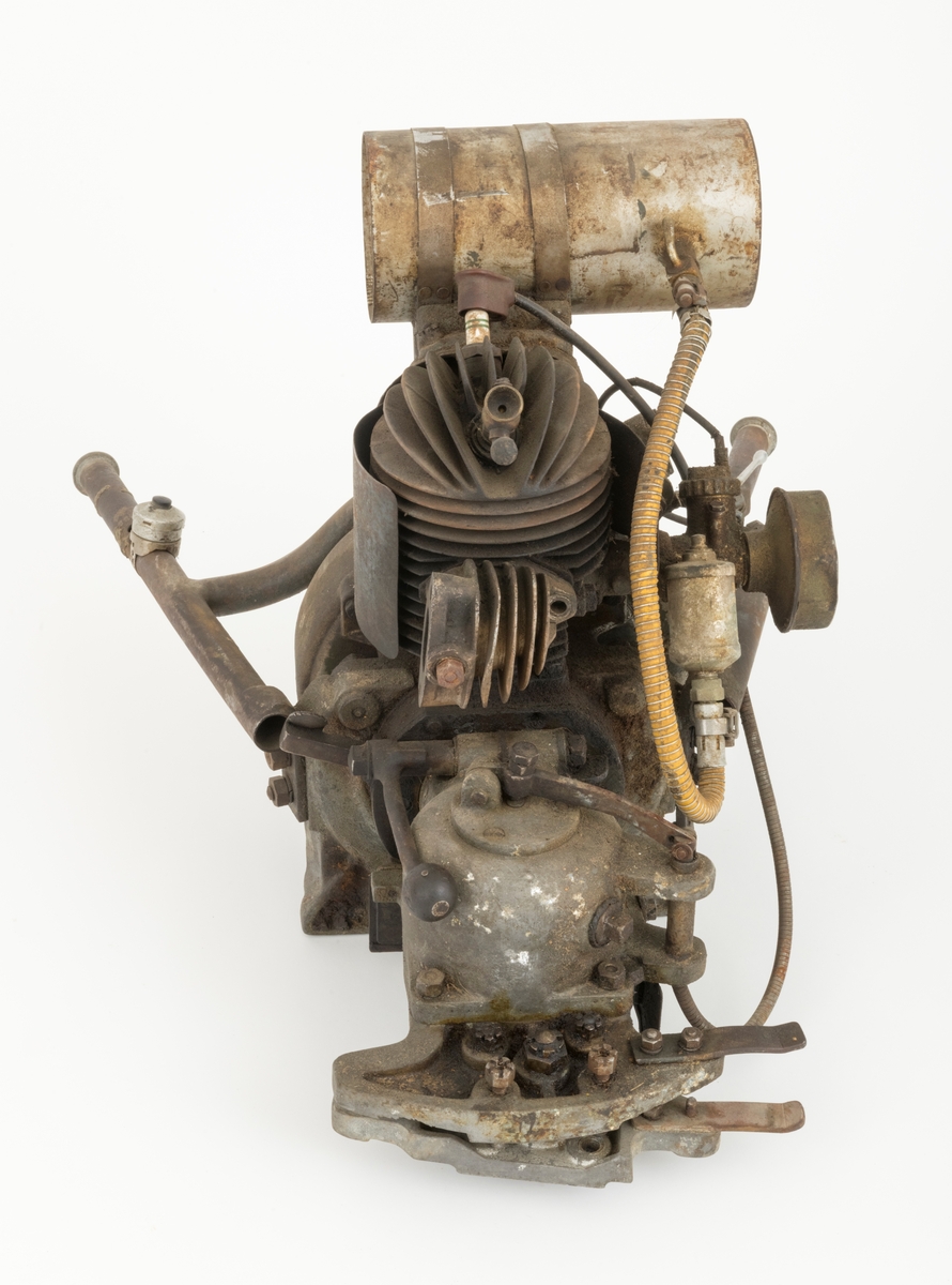Motor til en tomanns motorsag fra den tyske Dolmar-fabrikken, sverdet og eksospotta (antatt ekspospotte, se SJF.14799) til saga mangler. Saga har to håndtak bak motoren. Det sitter en tennplugg på toppen av motoren.