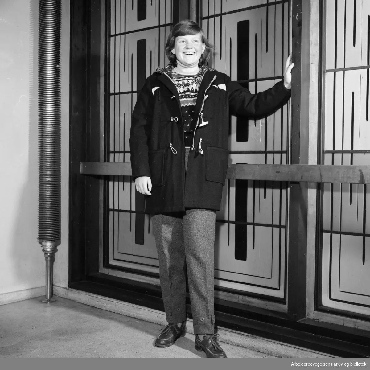 Høstens og vinterens nyheter i barneklær. Anne på 14 år med sort duffelcoat og benklær i grå vadmel. November 1956.
