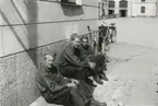 Tre soldater sitter vid en kasernbyggnad i Umeå, 1940.

Troligen på området för K 4, Norrlands dragonregemente.

Bildtext vid foto: 