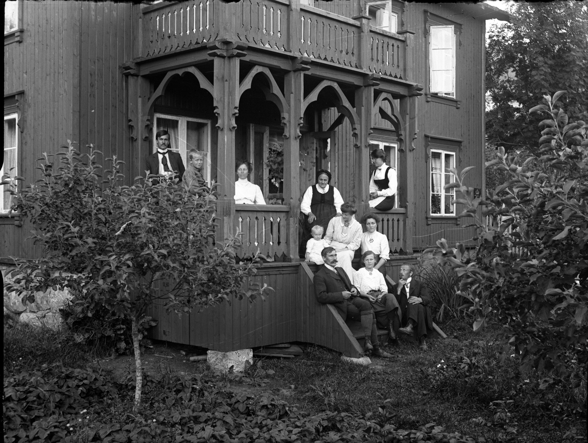 Fotosamling etter Kjetil Skomdal (1881-1971). Fotografen virket i perioden 1910 til 1960 og hadde eget mørkerom hvor han også tok imot film fra andre fotografer. I perioden var han også postbud i Fyresdal. Portrett av folk på trappen til Jorunn Bandaksli.
