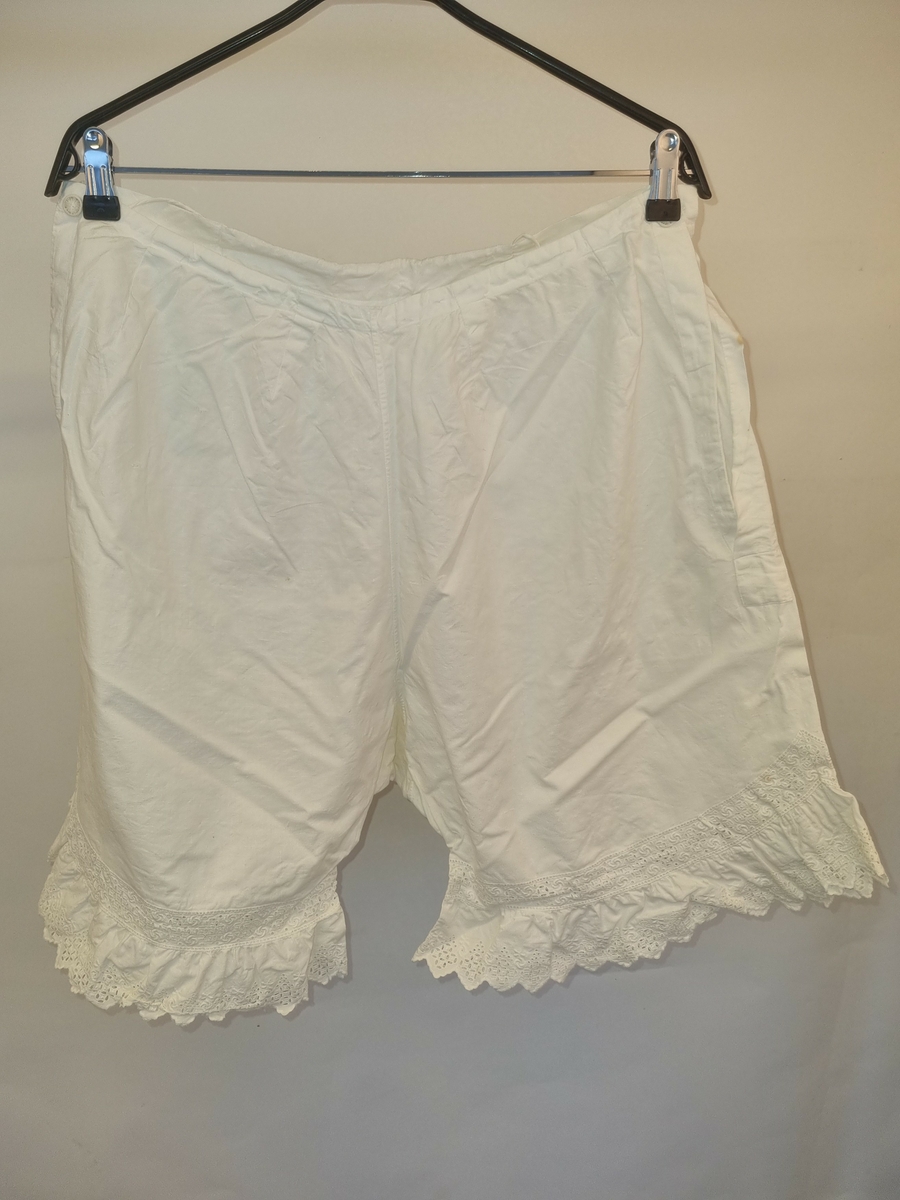 Bomull toskaft, hvit.
Åpning i sidene med trukket lerretsknapp.
Løpegang og trekksnor midt bak.
Nede på bena kapper av engelsk broderi.
Maskinsøm.
Merket: "H S"