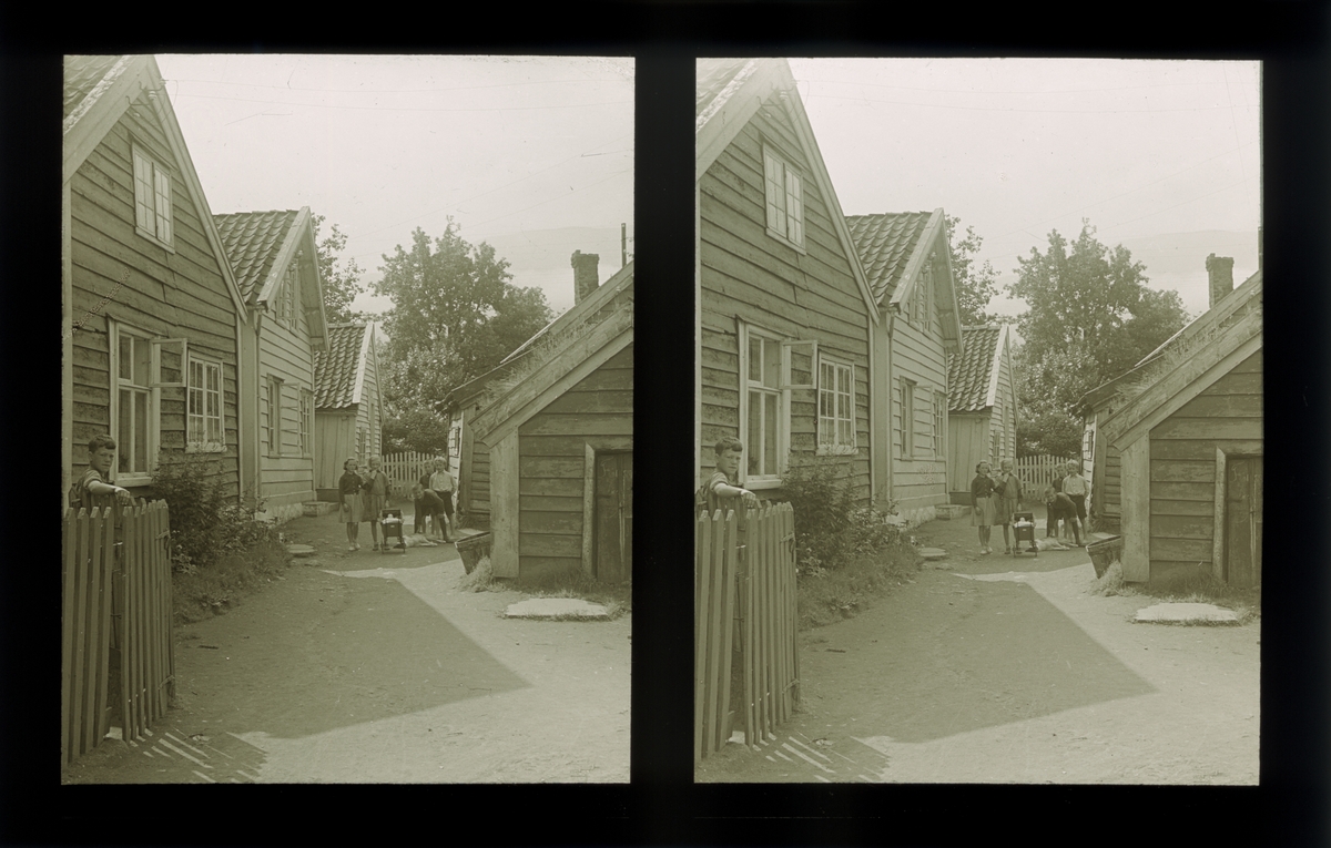 Trehusbebyggelse. Barna poserer for fotografen på tunet. Tilhører Arkitekt Hans Grendahls samling av stereobilder.