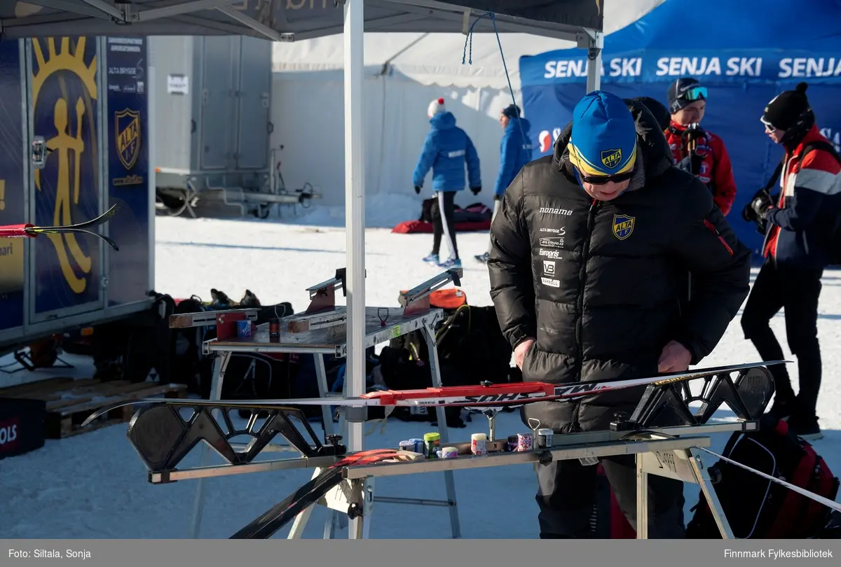 Skismøring er i gang utenfor telt til Alta I.F. Nord-Norsk Mesterskap (NNM) på ski arrangeres hvert år på omgang mellom Nordland, Troms og Finnmark Skikrets. I mars i 2019 mesterskapet ble arrangert i Vadsø i Finnmark.