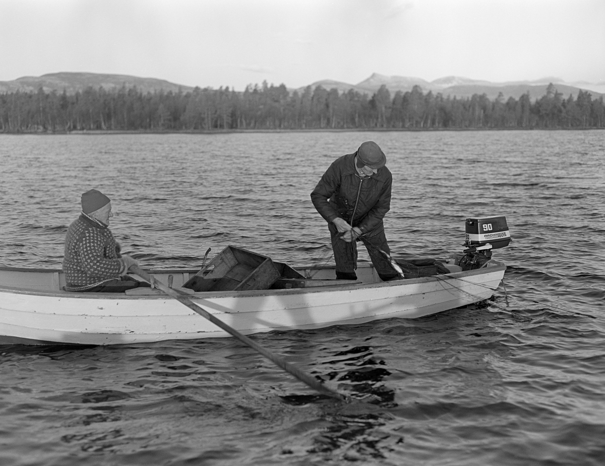 Joseph Bakken og Jo Bakken fra Tufsingdalen fisker sik med garn ved Kløvstenen, litt sør for Kløvstenodden, nær Tufsingdeltaet på vestsida av innsjøen Femund. Denne lokaliteten ligger i Os kommune i Nord-Østerdalen. Karene er fotografert i en kvitmalt, klinkbygd trebåt med tverr akterende, der det var montert en påhengsmotor. Da dette fotografiet ble tatt lå imidlertid båten stille. Joseph satt ved årene for å holde farkosten i en stabil posisjon mens Jo trakk garnet og plukket fisken ut av maskene. Fotografiet ble tatt i oktober 1978. På denne årstida besto fangstene hovedsakelig av sik.