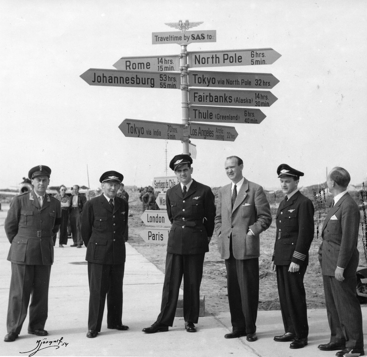 Flybesetning fra SAS og andre foran veiviseren på Bodø flyplass under mellomlanding på tur fra Oslo til Tokyo med DC-6B.