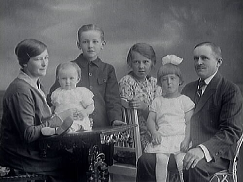 Trävaruhandlare Gottfrid Andersson med familj, hustrun Teresia f. Johansson och fyra barn: Harriet Anna Terese som sitter på bordet, Sven Gösta Gottfrid, äldsta dottern Signe Vera Alica och Ingrid Margareta i faderns knä. Gottfrid var delägare i Varbergs Träförädling, grundad 1933, tillsammans med fabrikör Karl J. Nilsson och grosshandlare Noak Johansson.