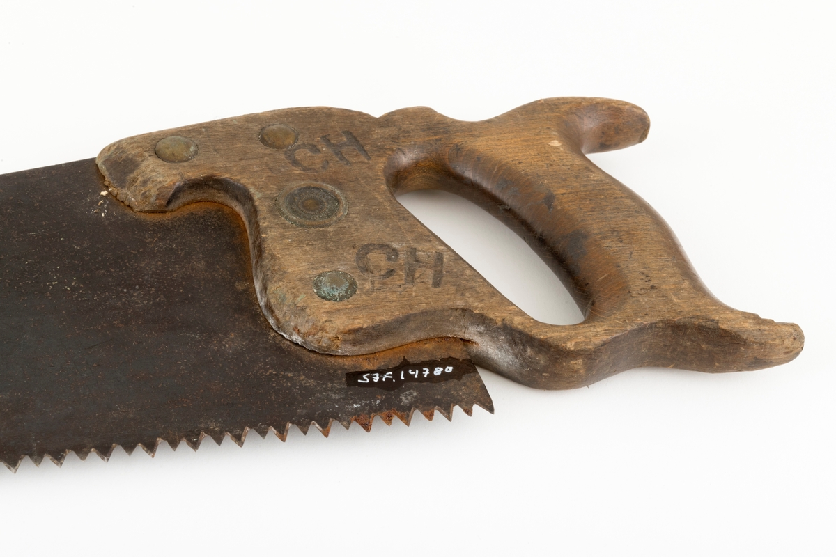 Sag, såkalt bladsag, brukt i snekkerarbeid. Saga er 64,5 centimeter lang, målt fra et punkt midt imellom handtakets ytterender og bladets ytterende. Bladet er snaut 55 centimeter lagt. Det er cirka 13,5 centimeter bredt i den bakre enden og 3,4 centimeter bredt i den fremre enden. Tannlinja er 54,5 centimeter lang og rettlinjet. Saga har 98 tenner som er cirka 0,4 centimeter lange. Den bakre halvdelen av bladryggen har en liten konveks krumning. Stålet i bladet (klingen) er om lag 0,1 centimeter tjukt. Saga har et trehandtak med et spor som den bakre enden av bladet er felt inn i og festet ved hjelp av fire gjennombrutte messingskruer. I den bakenforliggende delen av handtaket er det et ovalt hull til å gripe i og aller bakerst er det to bakovervendte «horn», hvorav det ene gav støtte til kløfta mellom tommelfinger og pekefinger. Handtaket har også ei lita, sirkelrund messingplate med innskriftetn «WARRANTED  SUPERIOR». Handtaket er også stemplet «CM», som antakelig er initialene til en tidligere eier,