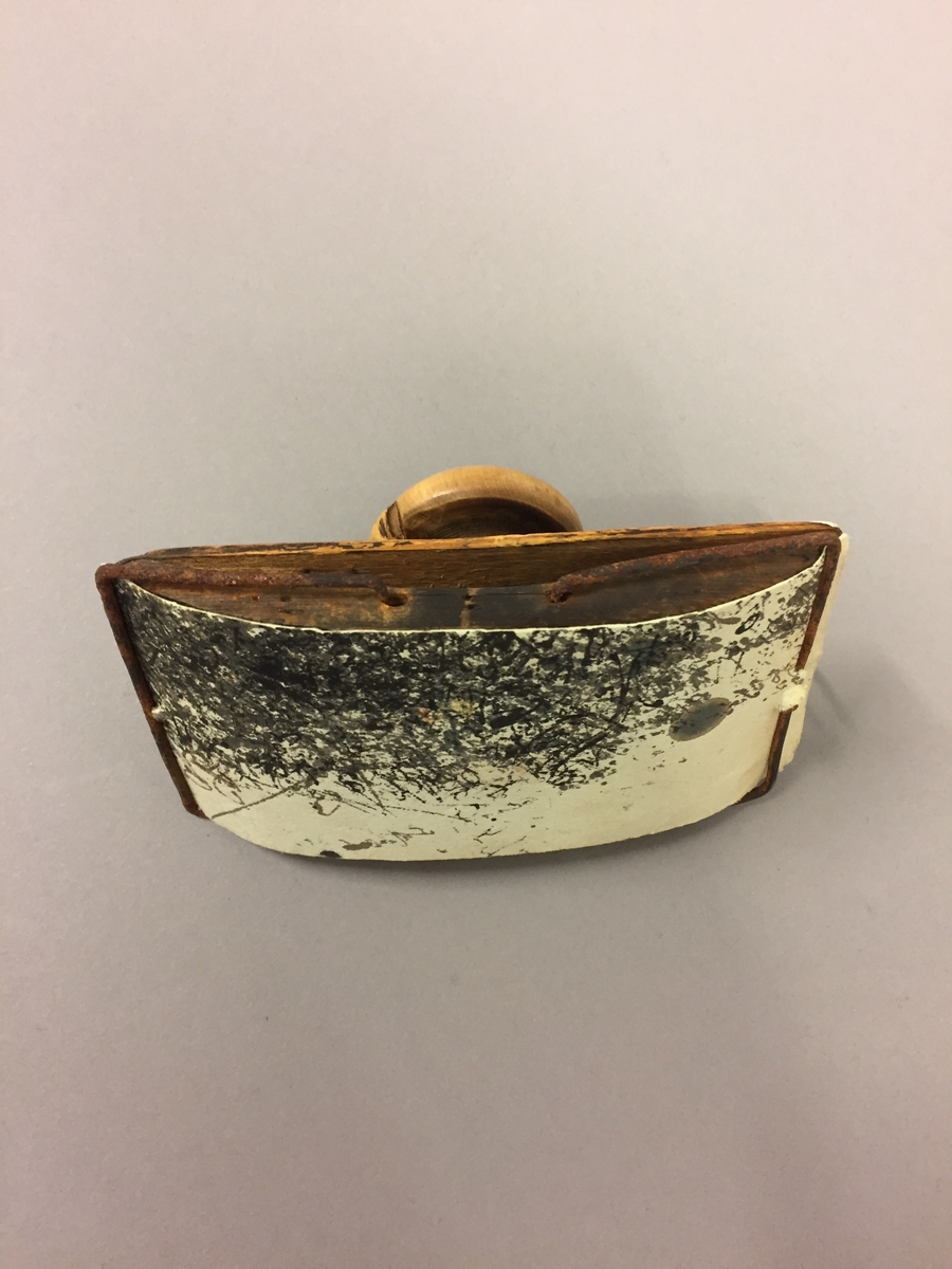 Presse laga i tre med metallklemmer på kvar side. Restar av blekk på undersida. Oppe på klemma
er det ein dreia knott.