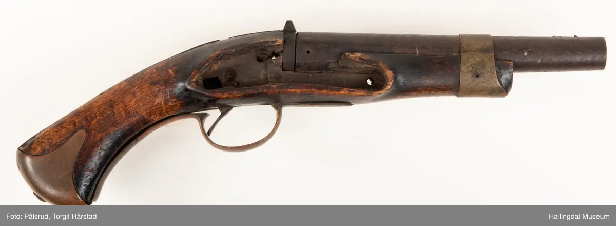 Kavaleripistol (rytterpistol), opprinnelig med flintlås. Mangler i dag låsen og ladestokk. Skjeftet er kuttet rett foran et messingbeslag. Messingbeslag på kolbe. Modell fra 1818, produsert på Kongsberg våpenfabrikk. Denne modellen hadde opprinnelig en løskolbe som kunne skiftes.
