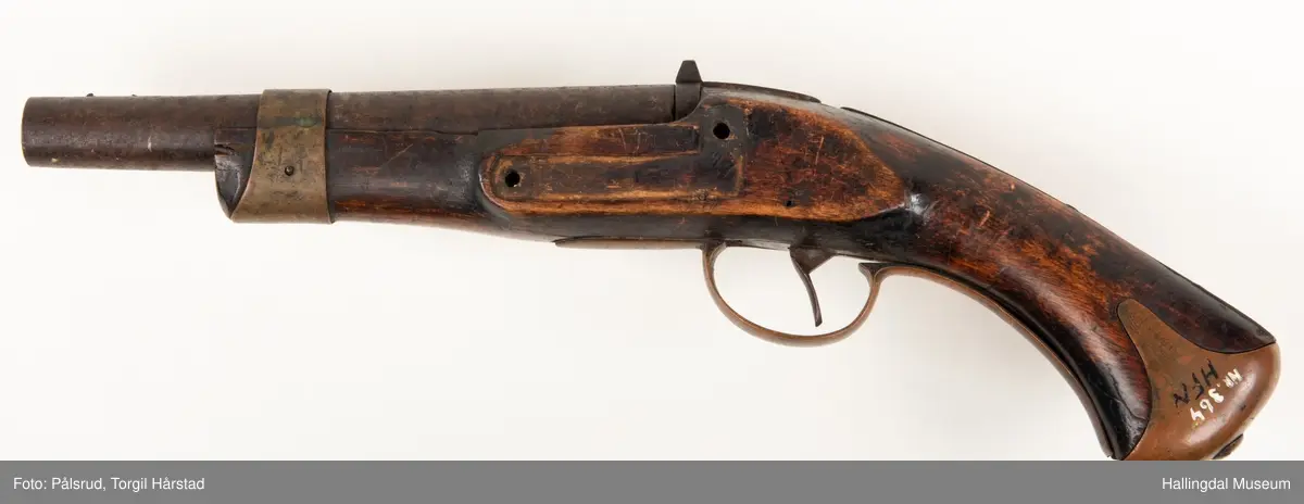 Kavaleripistol (rytterpistol), opprinnelig med flintlås. Mangler i dag låsen og ladestokk. Skjeftet er kuttet rett foran et messingbeslag. Messingbeslag på kolbe. Modell fra 1818, produsert på Kongsberg våpenfabrikk. Denne modellen hadde opprinnelig en løskolbe som kunne skiftes.