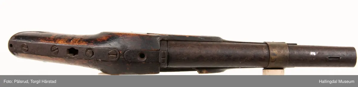 Kavaleripistol (rytterpistol), opprinnelig med flintlås. Mangler i dag låsen og ladestokk. Skjeftet er kuttet rett foran et messingbeslag. Messingbeslag på kolbe. Modell fra 1818, produsert på Kongsberg våpenfabrikk. Denne modellen hadde opprinnelig en løskolbe som kunne skiftes.