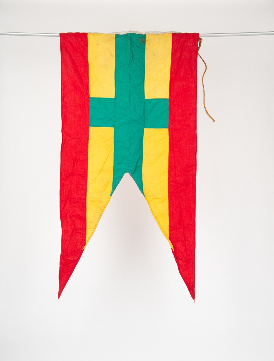 Signalflagg med to splitter. Rød horisontal stripe øverst og nederst, grønt kors på gul bakgrunn midten. Tau med messingkrok i innerkanten.