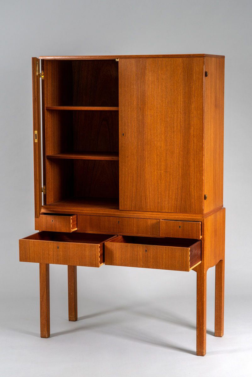 Skap på høye bein. To skapdører, en rekke med 3 skuffer og en rekke med 2 skuffer under, alle låsbare. Har tilhørt Sara Fabricius.